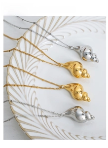 Polished gold and silver seashell pendants on beaded chains displayed on a white plate