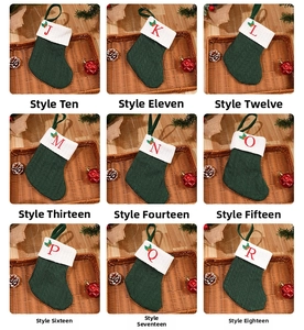 Detail of green knitted Christmas stockings with white cuffs and red letter embroidery