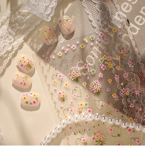 Detail of floral nail stickers with gold hearts and ribbon designs for nail art