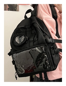 Detail of black ita bag featuring a large transparent window and heart-shaped pouch charm