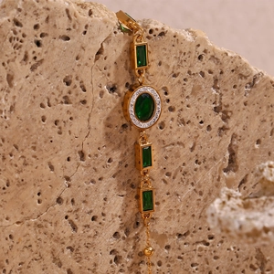 Macro detail of 18K gold-plated bracelet with emerald-green stones on stone background
