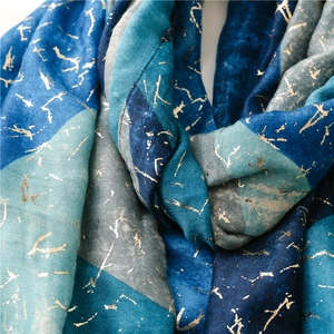 Detail of blue geometric scarf with metallic gold foil cracked pattern texture