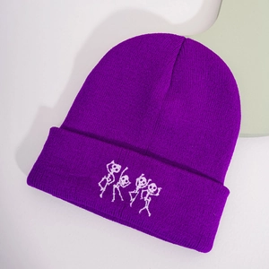 Détail du bonnet en tricot violet avec une broderie de squelette blanc sur le revers