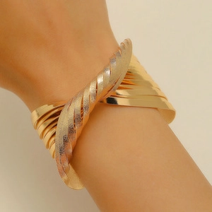 Detail of layered gold ethnic cuff bracelet with polished and matte textured finish