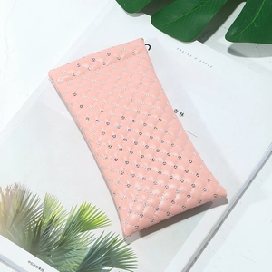 Pink quilted glitter PU leather sunglasses pouch on white magazine and green leaves