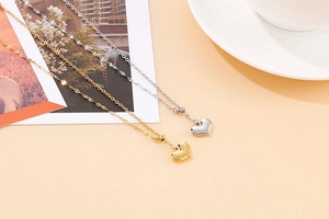 Macro shot of stylish gold and silver heart-shaped pendant necklaces on warm background