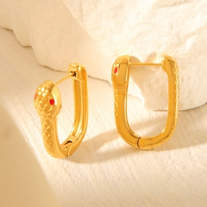 Boucles d'oreilles serpent plaquées or 18 carats avec yeux rouges sur fond texturé