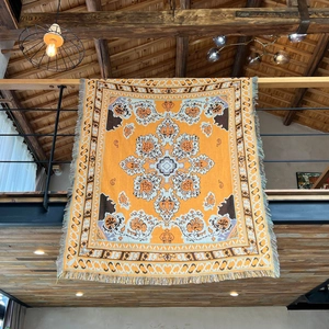 Bohemian orange woven camping blanket with fringe hanging in a rustic wooden loft