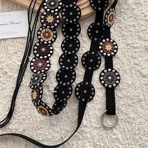 Détail de ceinture bohème en cuir noir avec fleurs colorées cloutées et boucle anneau