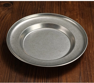 Macro shot of vintage style stainless steel pasta plate on a dark wooden tabletop
