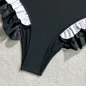Close-up of black swimsuit bottom featuring black and white double-layered ruffle trim details