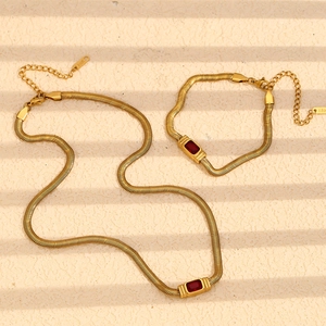 Detailed macro of 18K gold-plated snake chain set with a red rectangle gemstone
