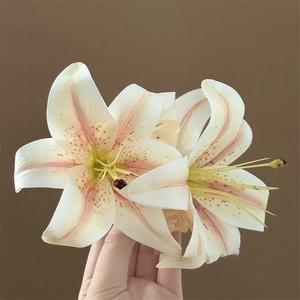 Dettaglio del fermaglio per capelli a forma di giglio con petali crema e venature reali