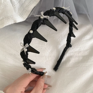 Detail of black spiked headband with sparkling rhinestone bow and woven texture