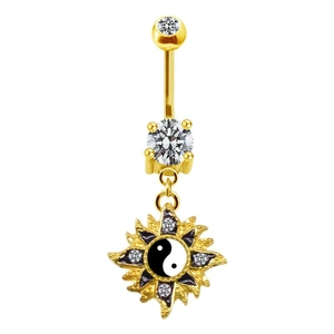 Vue détaillée d'un piercing de nombril doré avec pendentif soleil et motif yin yang