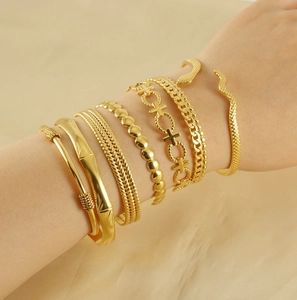 Detail of 18K gold-plated twisted bangles and stacked bracelets on a woman's wrist