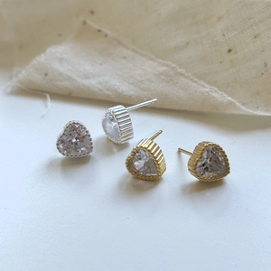 Macro shot of heart-shaped earrings in gold and silver finish with zircon crystals