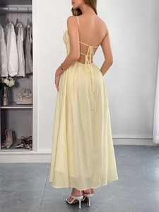 Detail view of the open-back design with crisscross tie-up straps on a light yellow dress