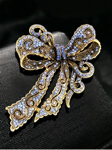 Detailed close-up of retro golden bow brooch with sparkling blue rhinestones