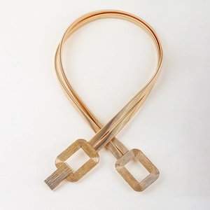 Close-up of gold spring chain belt featuring interlocking rectangular metal buckles