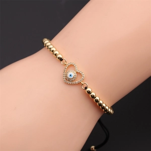 Détail du bracelet cœur œil porte-bonheur en or avec zircons et cordon tressé noir