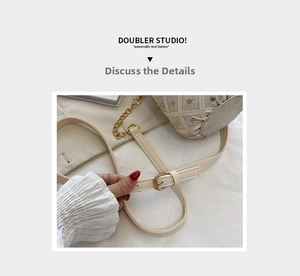 Detail of beige crossbody bag with gold chain strap and metal rivet embellishments