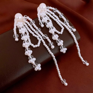 Macro shot of elegant multi-layered pearl tassel earrings on dark leather display
