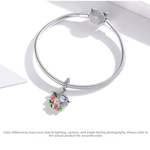 Detail of S925 silver snake chain bracelet with crystal cat clasp and floral bird charm