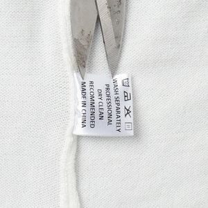 Detail view of the wash care label on a white knitted fabric showing laundry instructions