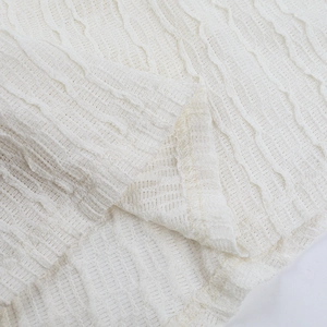 Vue macro du tissu blanc de robe de soirée montrant des textures plissées ondulées