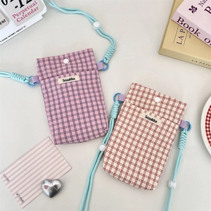Close-up of plaid fabric phone pouches with snap buttons and adjustable neck straps