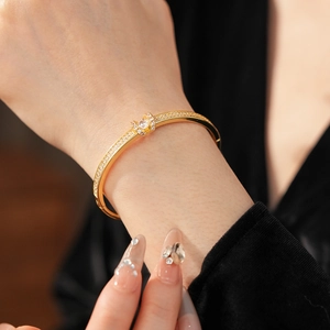 Detailed view of a gold-plated oval bangle with shimmering pavé set diamonds on a wrist
