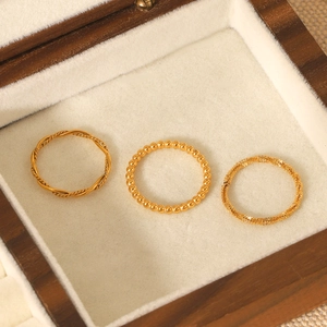 Detailed view of three stackable gold rings in twisted and beaded styles in a wooden box