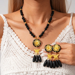 Close-up of black resin floral pendant necklace and matching butterfly earrings set
