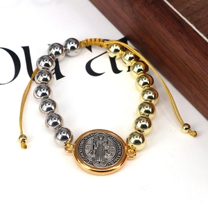 Detail von zweifarbigen Gold- und Silberperlen mit Benediktusmedaille an Kordelarmband