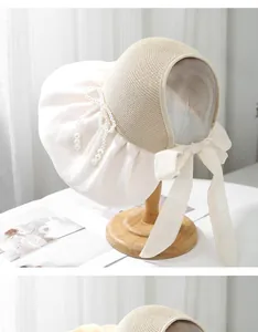 Detail of elegant straw sun hat with pearl bow ornament and cream fabric ribbon