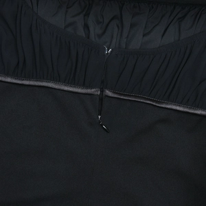 Détail de la fermeture éclair invisible et de la texture froncée du tissu noir de la robe