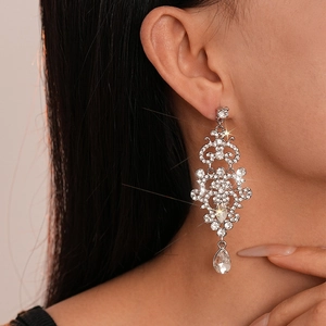 Close-up of sparkling rhinestone teardrop tassel earrings worn by a model in silver finish