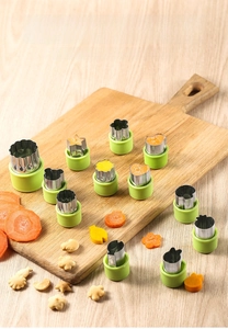 Close-up of 12-piece stainless steel cookie cutters with green handles on a wooden board