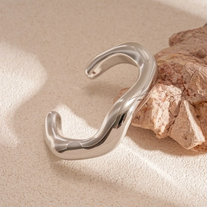 Dettaglio macro del bracciale in argento lucido con forme irregolari e stile metallo liquido