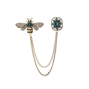 Vintage gold bee chain brooch with emerald green stones and pearls on white background