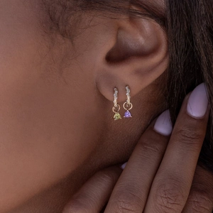 Detail of gold hoop earrings with multi-color gemstones and pavé stones on model