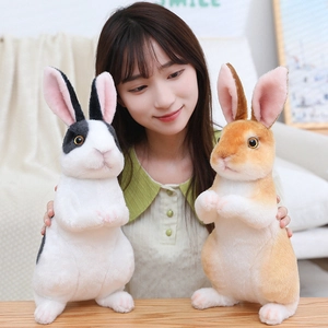 Realistic plush bunny toys in black-white and yellow-white fur held by a model