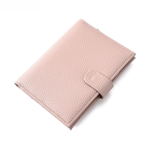 Detail shot of pink pebble grain leather passport wallet with secure snap button closure