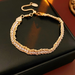 Detail of adjustable gold chain bracelet with sparkling round crystals on black leather