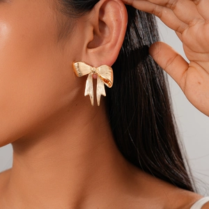 Close-up of a model wearing the golden metallic bow stud earring in a modern style