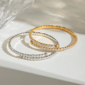 Elegant gold and silver spiral bracelets with pavé zircons on a white surface