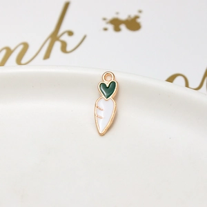 Macro detail of white carrot charm with green heart leaves and gold metal edges