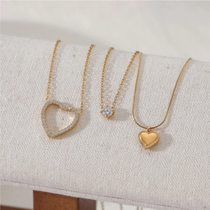Elegant gold heart pendant necklaces with crystals on a jewelry display stand
