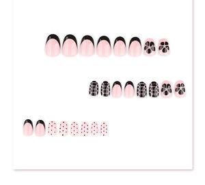 Détail de faux ongles roses avec pois noirs, bordure française et motifs floraux chic